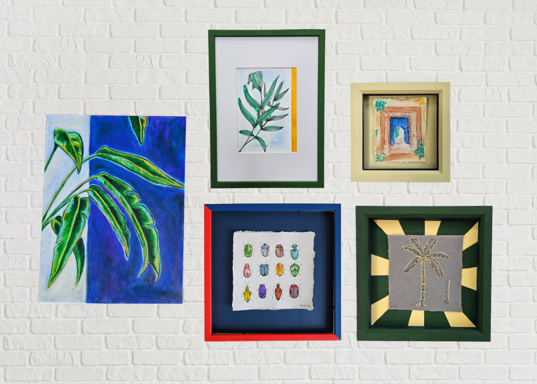 Collection of framed artworks on a white brick wall