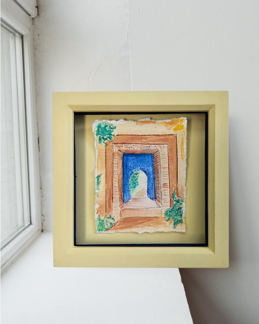 Framed artwork on a white surface with a window in the background