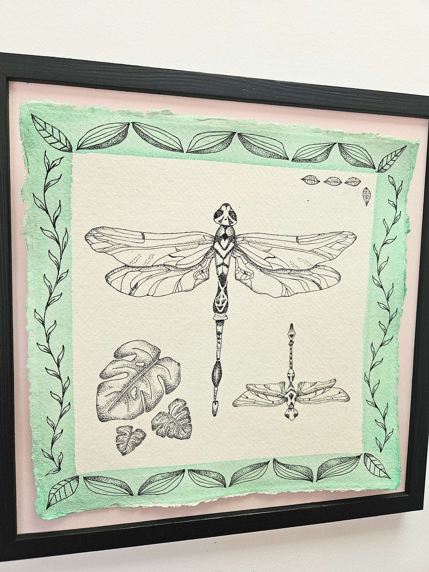 Framed artwork with a dragonfly illustration on a green and white background