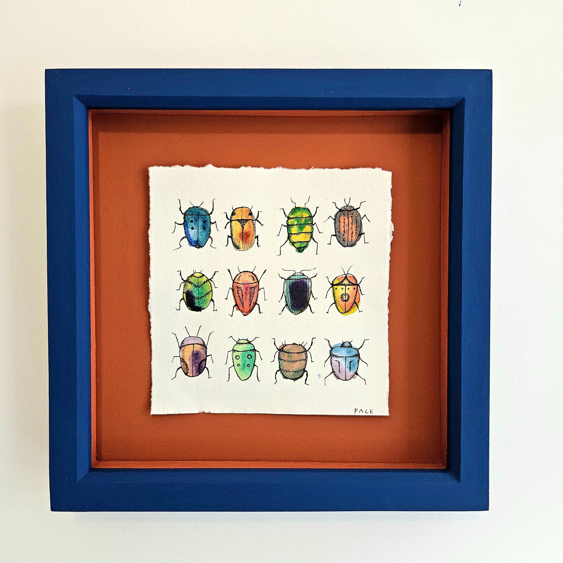 painting of beetles mounted on orange in a blue frame