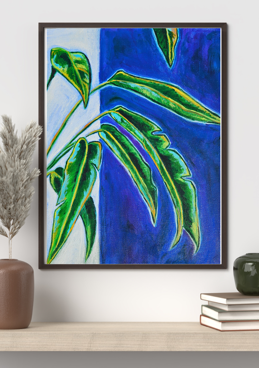 Framed artwork with green leaves on a blue background, displayed on a wall.