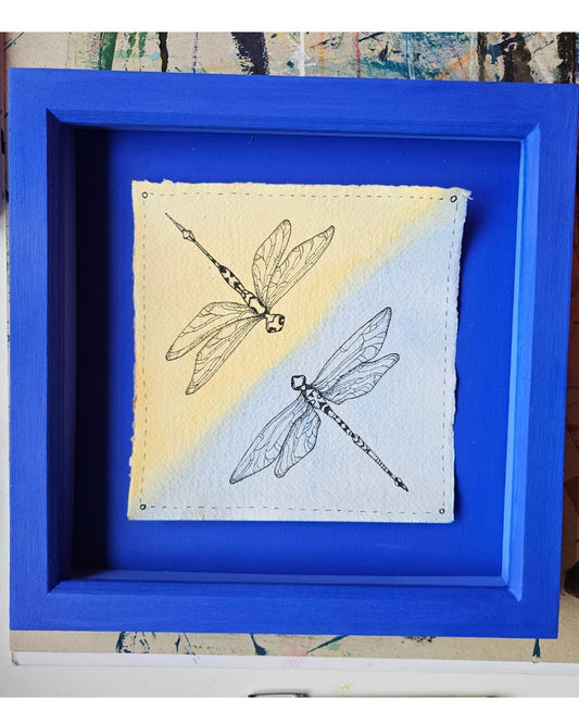 Framed artwork with dragonfly design on a yellow and blue gradient background