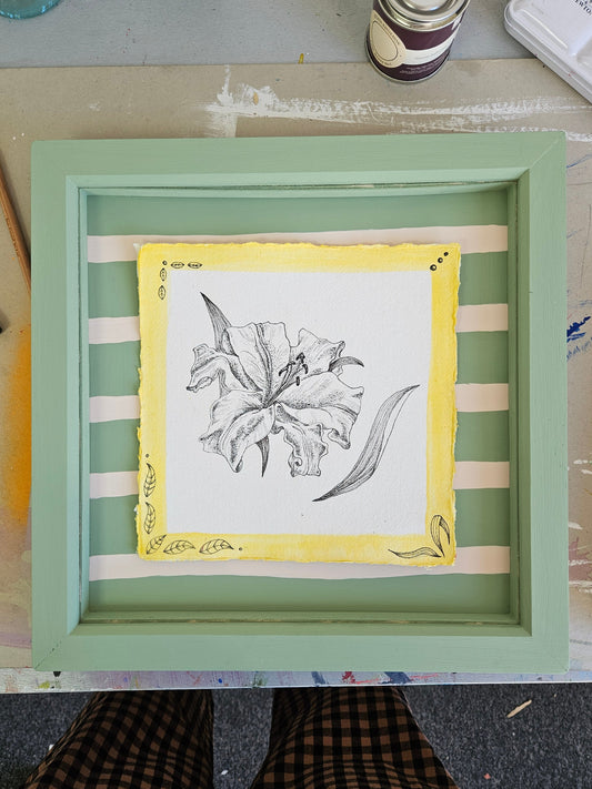 Framed artwork with a illustration of a Lily on a striped background