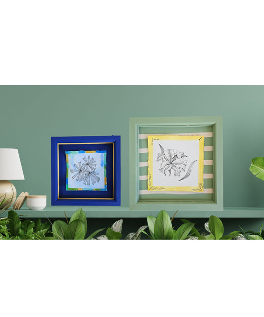 Two framed artworks on a green wall with plants below.